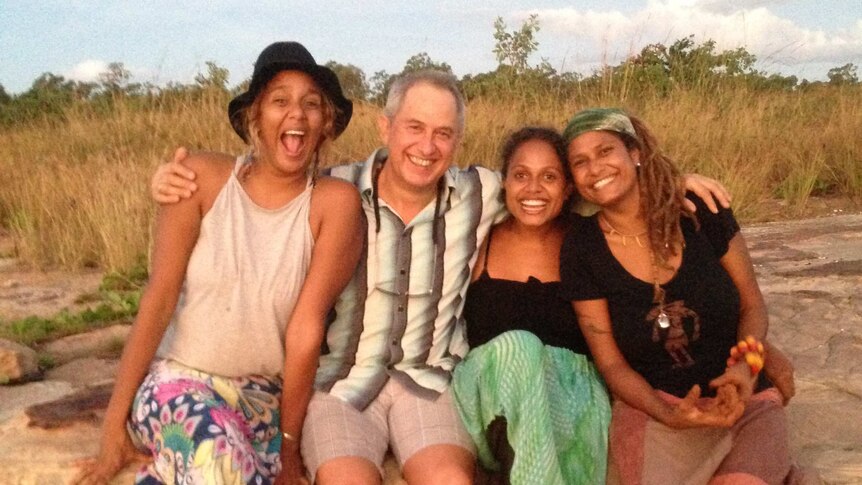 Grace, Michael, Noni and Alice Eather sit on a rock ledge, smiling and embracing each other