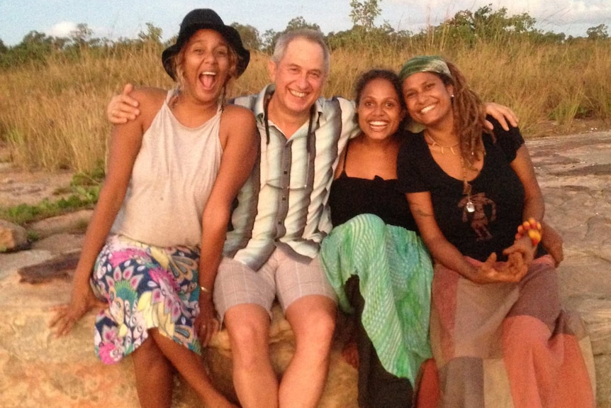 Grace, Michael, Noni and Alice Eather sit on a rock ledge, smiling and embracing each other