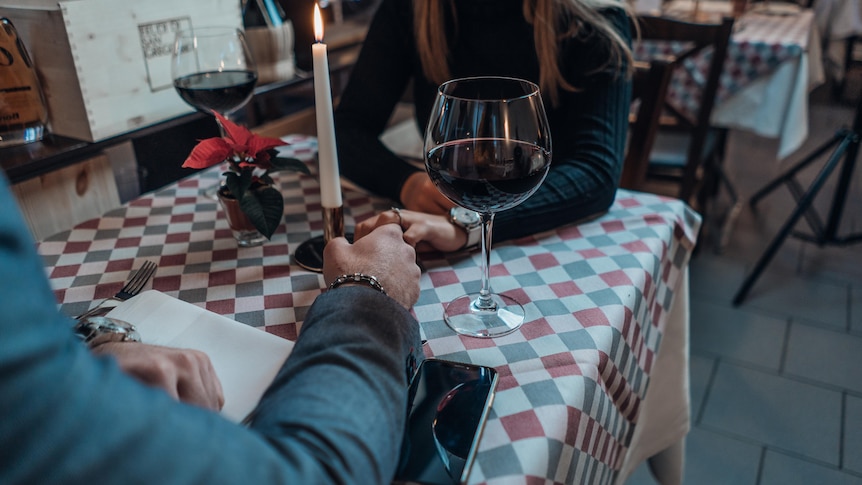 Couple holding hands over a candlelit dinner