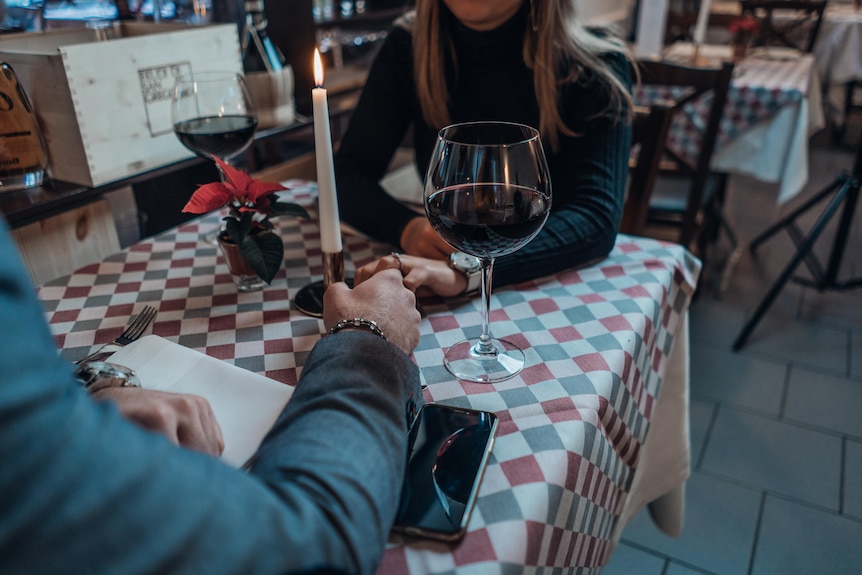 Couple holding hands over a candlelit dinner