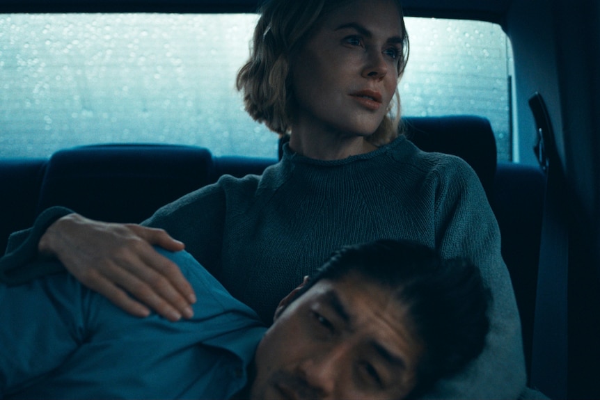 A TV still of Brian Tee lying in Nicole Kidman's lap in the back of a cab as she gazes out the window.
