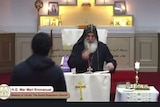 a bishop at an assyrian orthodox church during a service before a person approaches and allegedley stabs him