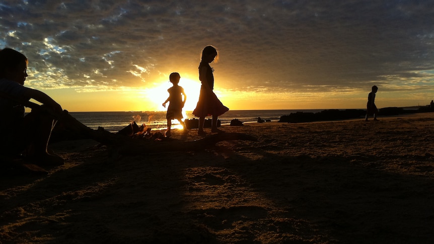 Silhouette of children in the Kimberley on a beach at sunset.