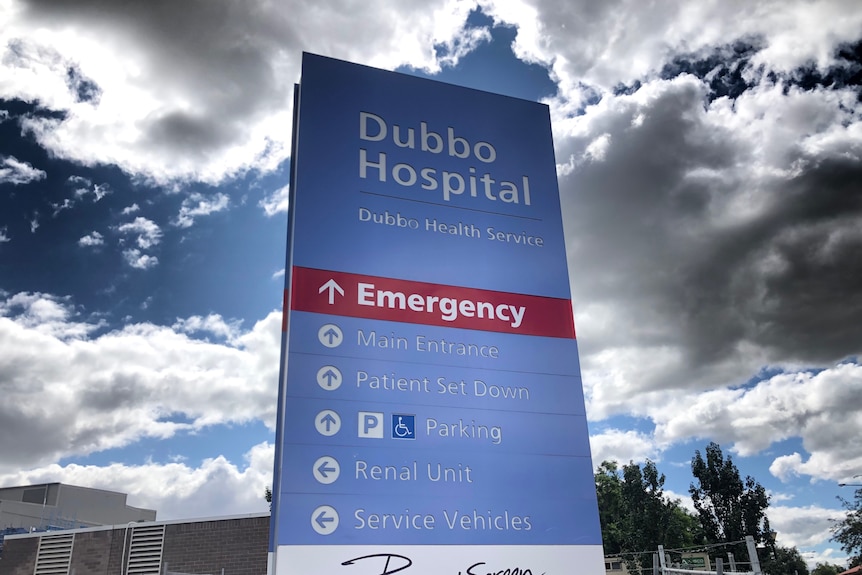 A towering sign for Dubbo Hospital against a cloudy blue sky.