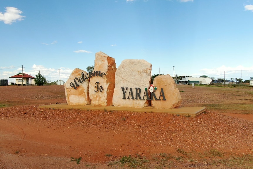 Welcome to Yaraka sign in a flat landscape with red dirt