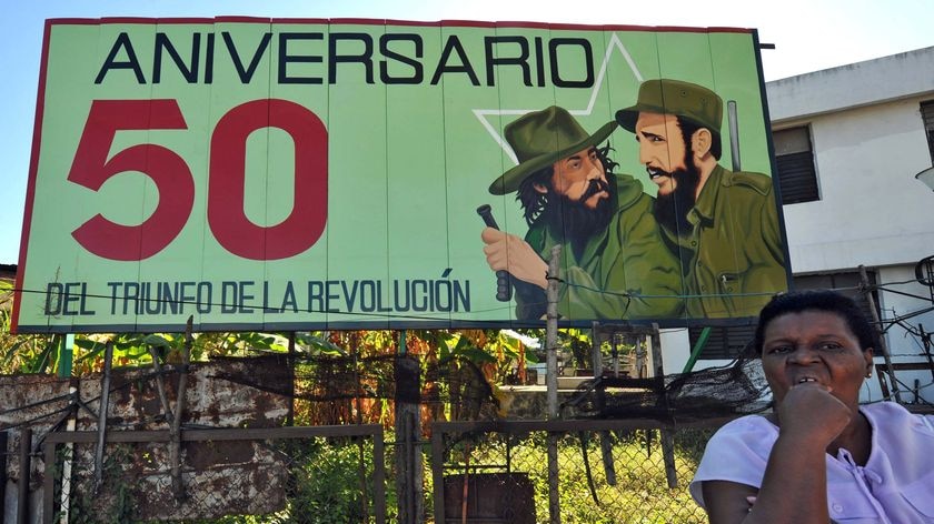 A woman waits at bus stop next to a political propaganda poster in downtown Santiago