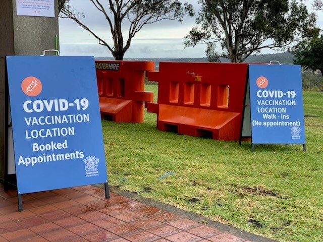 Two blue signs for the COVID-19 vaccination clinic in Toowoomba.  advertise