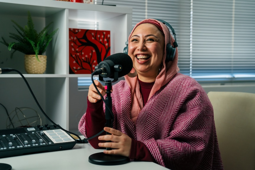 Roots TV Chair Aisha Novakovich laughing and holding a microphone