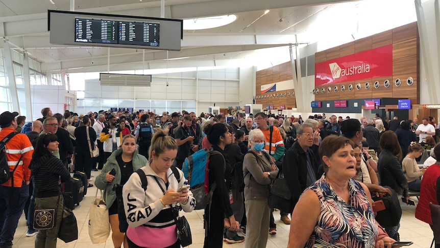 People waiting in an airport concourse with a Virgin Australia sign above them