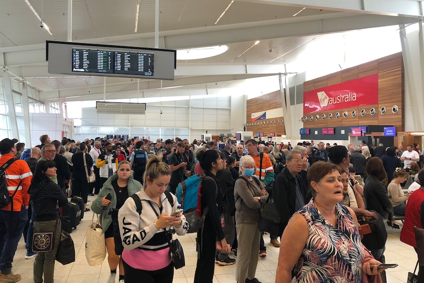 People waiting in an airport concourse with a Virgin Australia sign above them