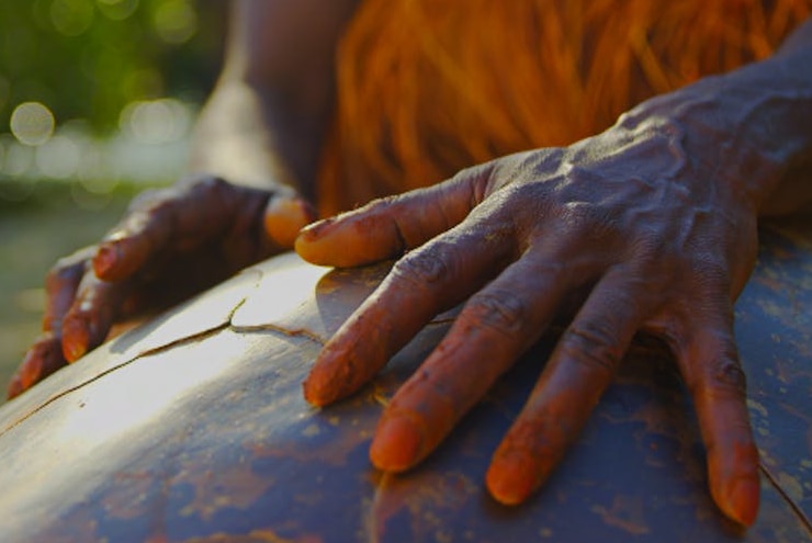 An indigenous man's hands stroke the shell of a turtle