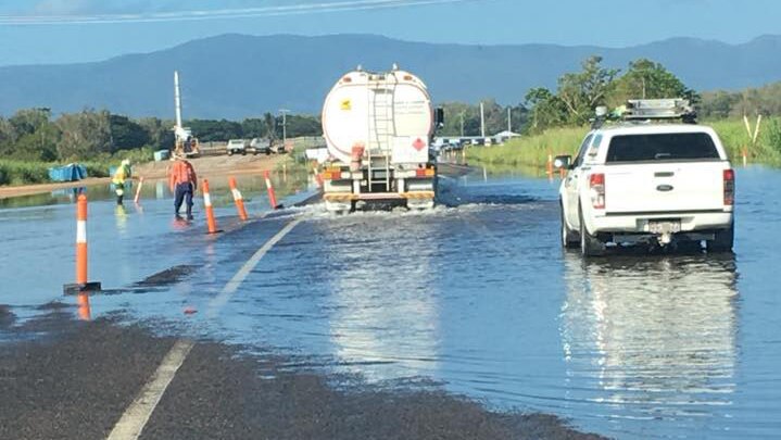 Truck and car drive through flooded Bruce Highway in north Queensland.