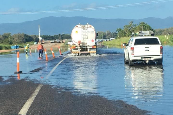 Truck and car drive through flooded Bruce Highway in north Queensland.