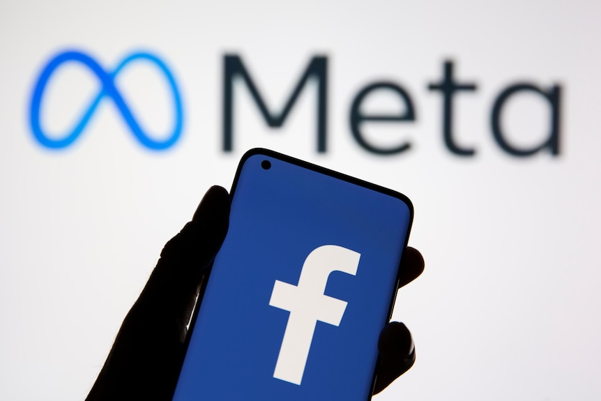A smartphone with Facebook's logo is seen in front of displayed Facebook's new rebrand logo Meta.