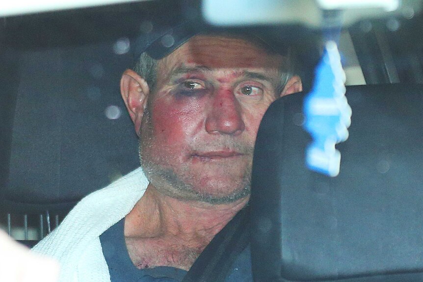 Gino Stocco sits in the back of a police vehicle as he is taken into Dubbo police station
