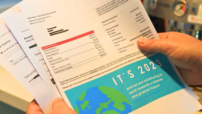 a close-up of a person holding several pages of a household power bill in their hands