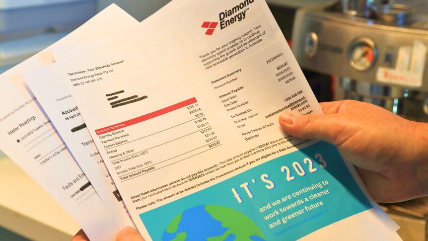 a close-up of a person holding several pages of a household power bill in their hands
