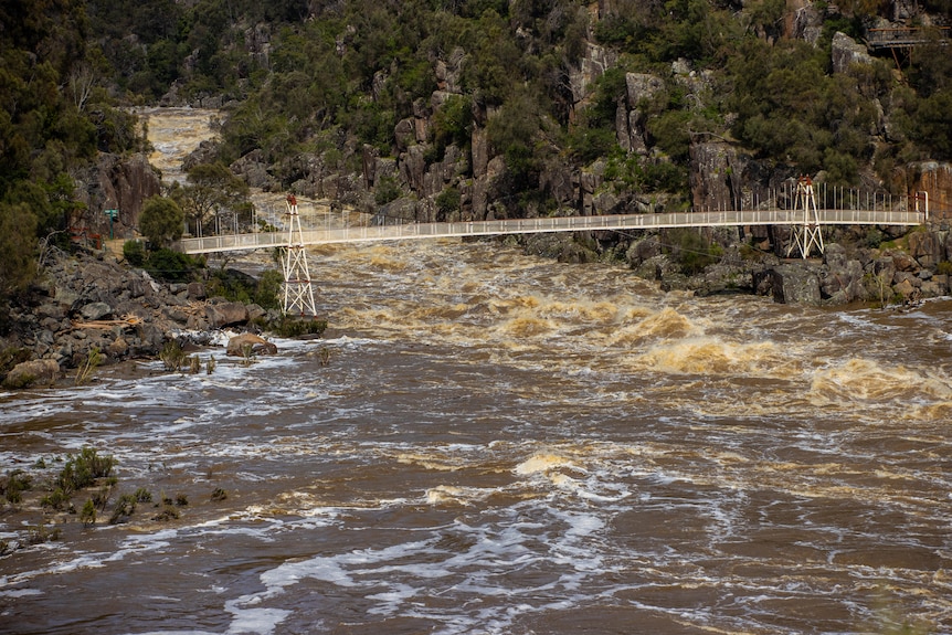 Flood water rushes under a bridge