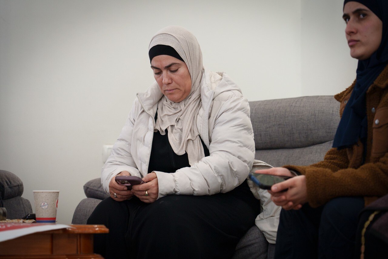 A woman siting on a sofa, looking at her phone with a concerned expression on her face.