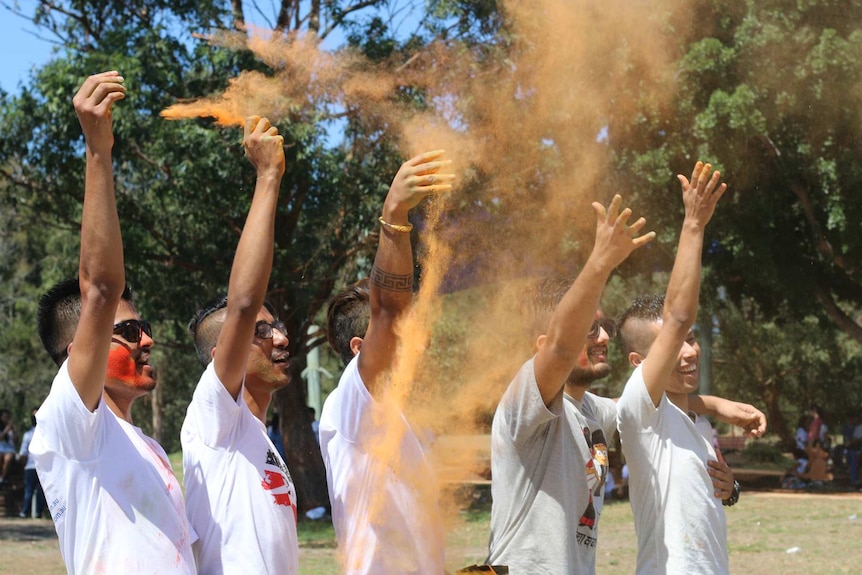 Young men throw coloured powder into the wind for the Hindu festival Holi at the South Sydney reserve.