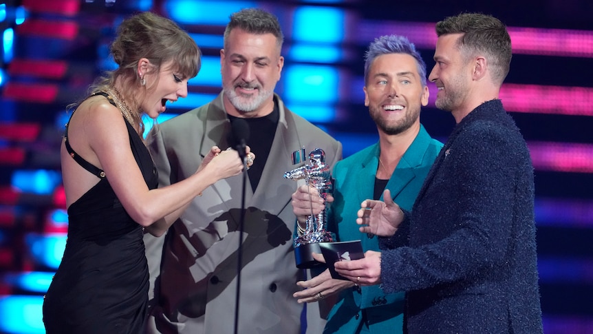 Taylor Swift accepts a moonman from three members of *NSYNC