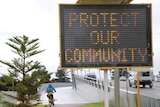 Road sign in front of bridge reads Protect our community, traffic and cyclist in background