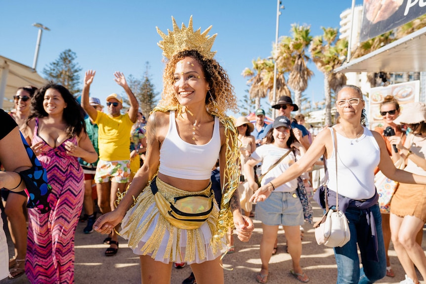 Une femme porte un casque doré dans une foule de danseurs.