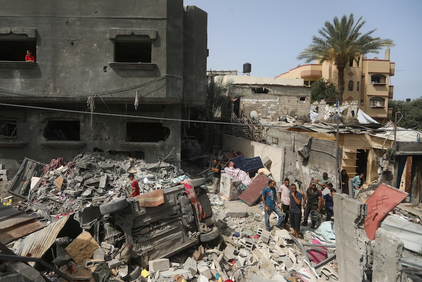 People walk through the remains of a bombed-out building surrounded by debris