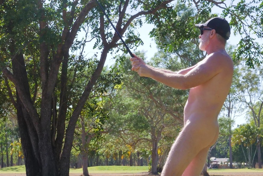 Man swinging golf club on golf green, wearing only shoes and a hat