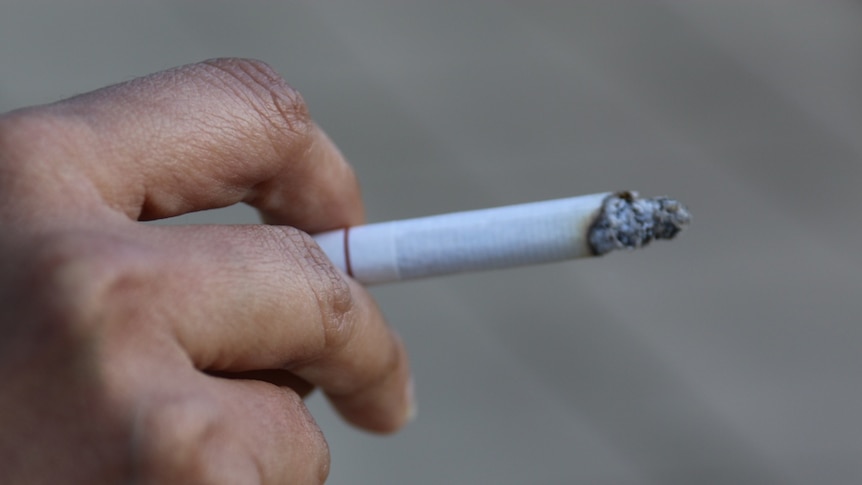 close up of women's hand holding a lit cigarette