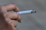 close up of women's hand holding a lit cigarette