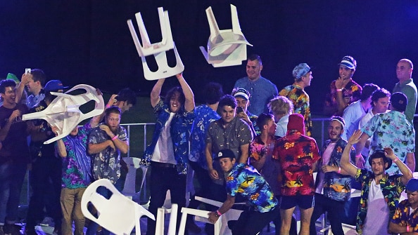 Group of men in coloured shirts throwing plastic chairs