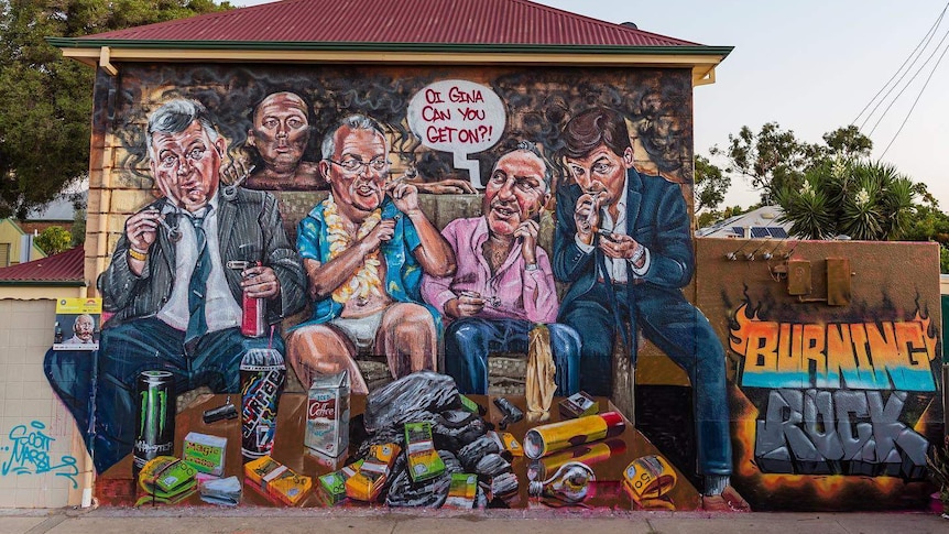 A mural on an old building of four men smoking black drugs from glass pipes