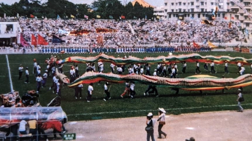 A photo of a soccer field with a giant banner display and a crowd in the background