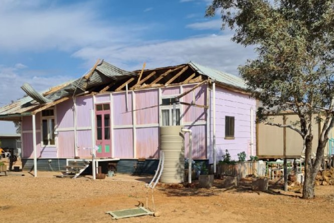 A purple Queenslander house with a damaged roof.