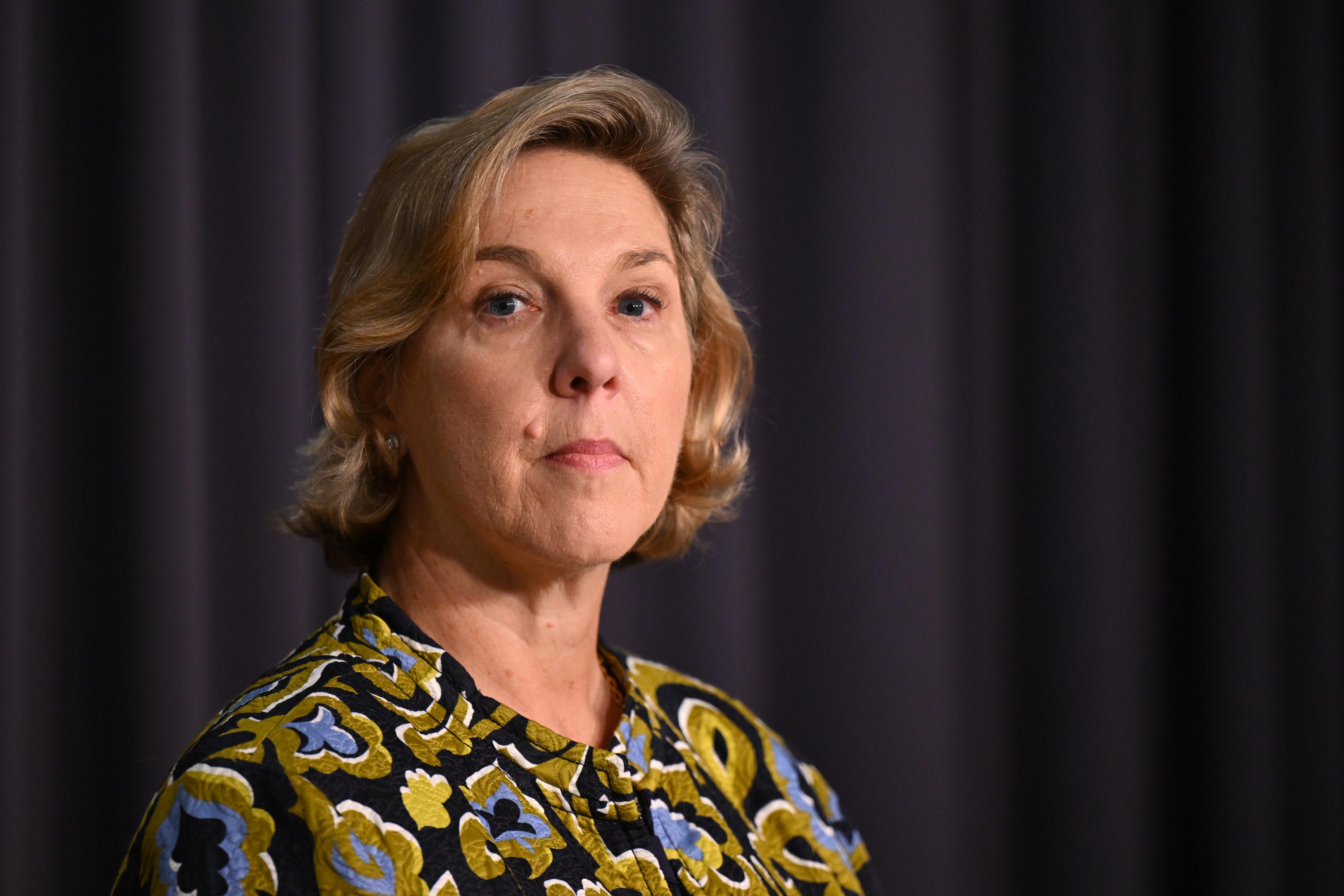 Denholm stands looking serious.