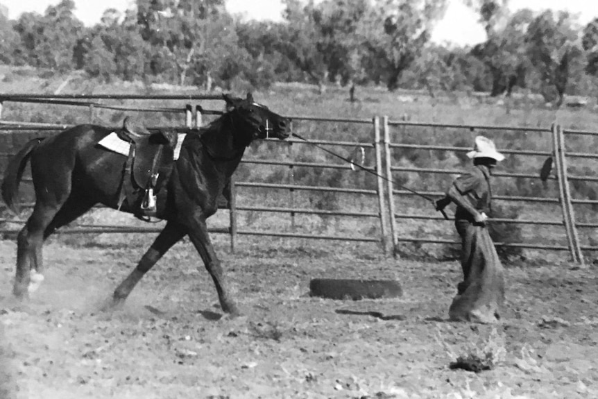 Black and white photo of man hopping in a sack and leading horse taken at a 1970s Kimberley rodeo