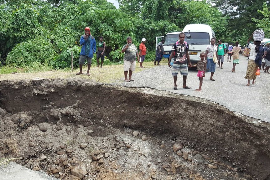 A large hole in the middle of a road where a bridge used to be.