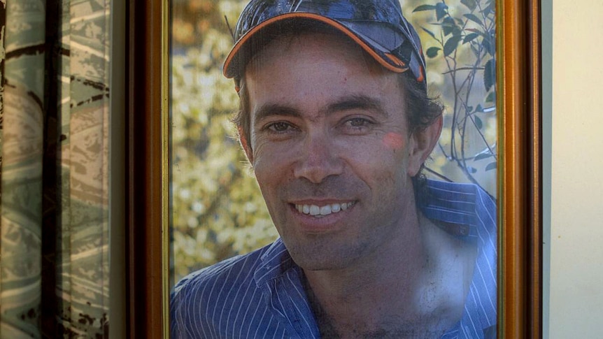 A framed photo of a smiling man, wearing a cap.