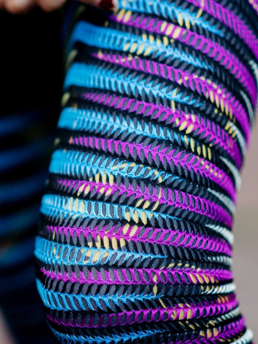 A close up of Ula's leg, covered by shiny multicoloured stockings.