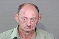 A mugshot of a balding man wearing a green shirt.