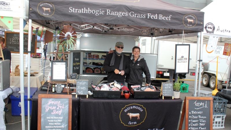 A man and a woman stand at a stall selling grass fed beef.