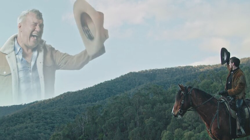 An apparition of Jimmy Barnes dressed as a cowboy in the sky above a mountain range. Kirin J Callinan looks at it atop a horse.