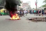 group of men gathered around burning tires on the street