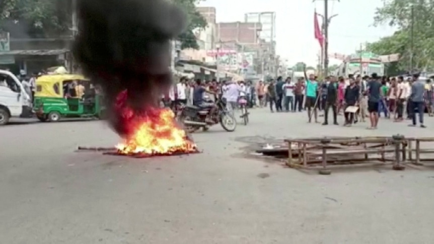 group of men gathered around burning tires on the street