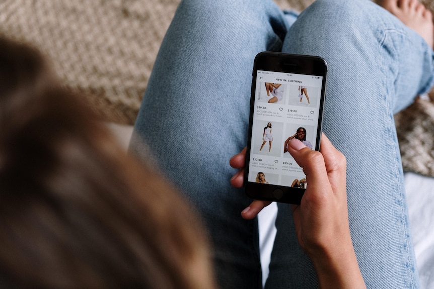 A woman scrolls through a clothes shopping site on her mobile