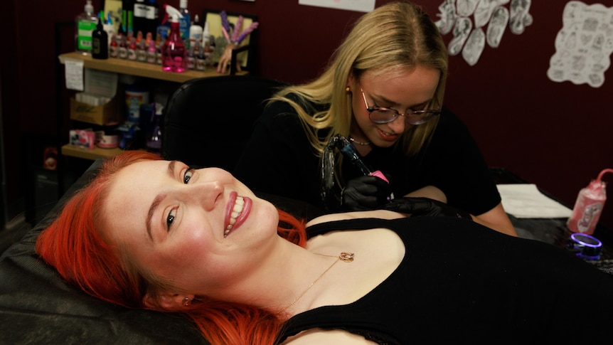 A client smiling as she's getting tattooed.