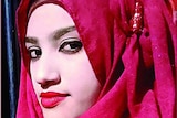 A woman with red lipstick wears a red headscarf.
