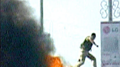 Under attack: A British soldier leaps from a tank after an angry crowd pelted it with petrol bombs