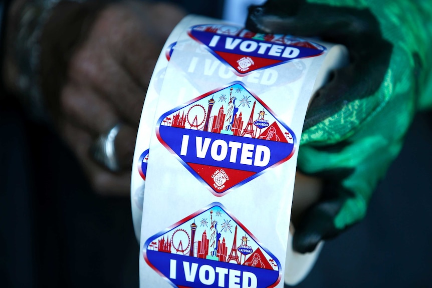 A US poll worker displays "I Voted" stickers.
